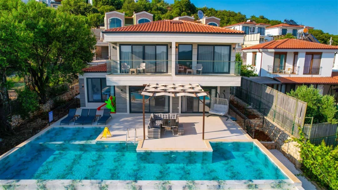 Önünde özel havuzu, güneşlenme alanı ve pergolalı oturma grubu bulunan iki katlı villa.