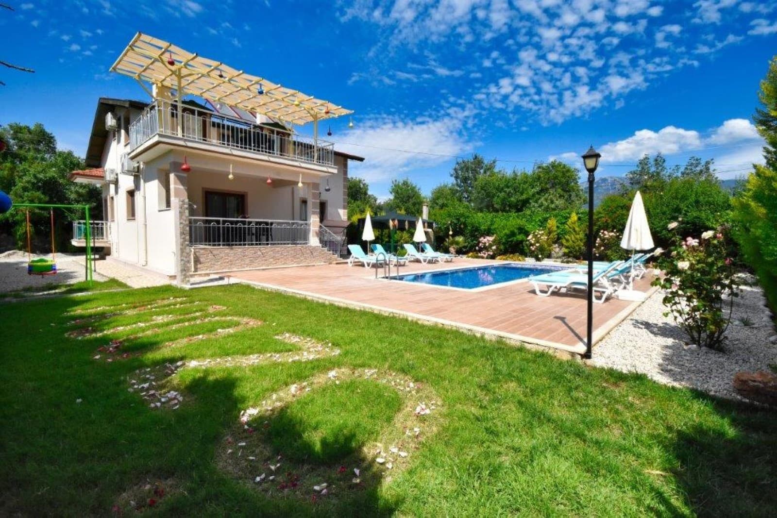 Bahçesinde havuz ve çim alan bulunan iki katlı villa.