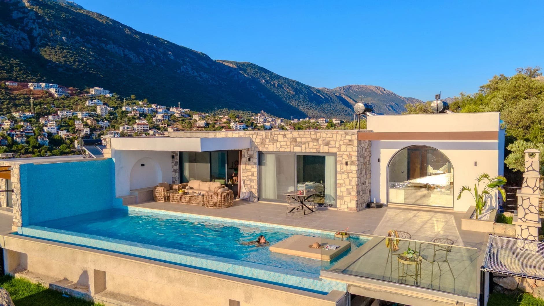 Dağ ve yerleşim manzaralı modern villanın önünde sonsuzluk havuzu var.