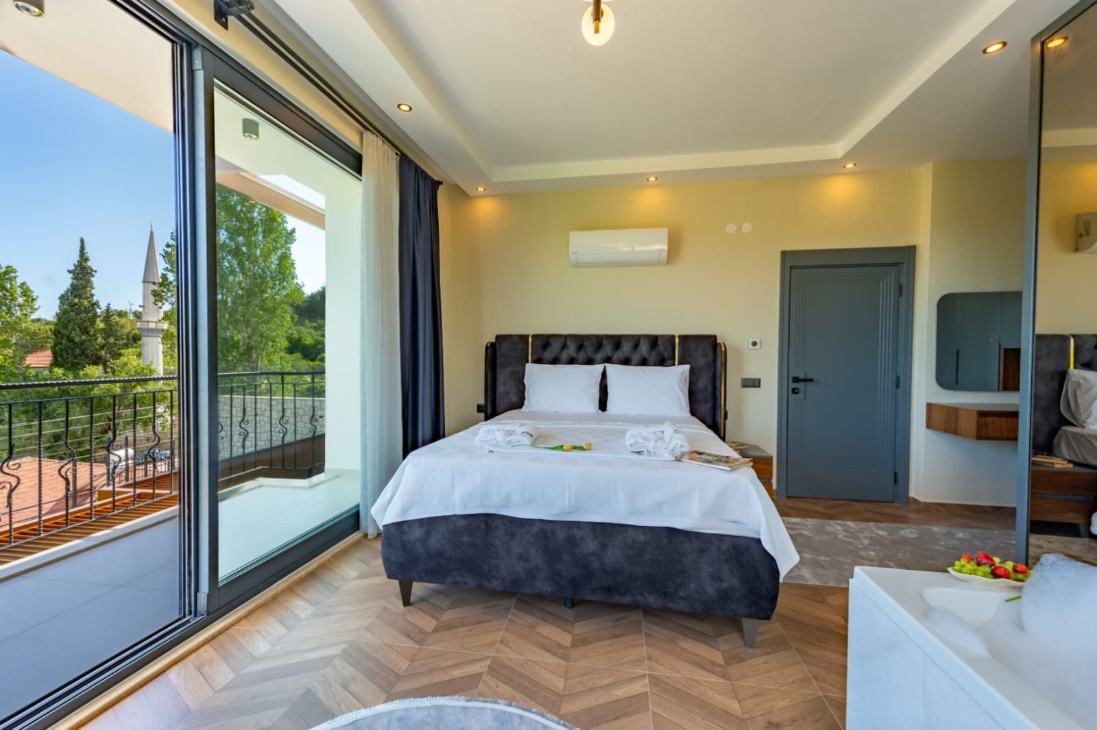 Ahşap parkeli yatak odasında koyu başlıklı çift kişilik yatak, balkon ve jakuzi yer alıyor.