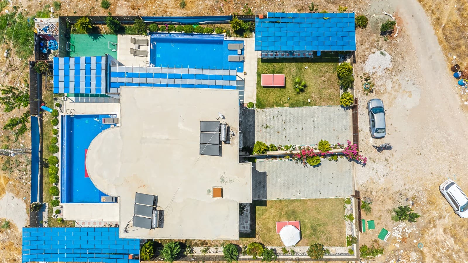 Havuzları, otoparkı ve bahçesi görünen villanın üstten drone çekimi.