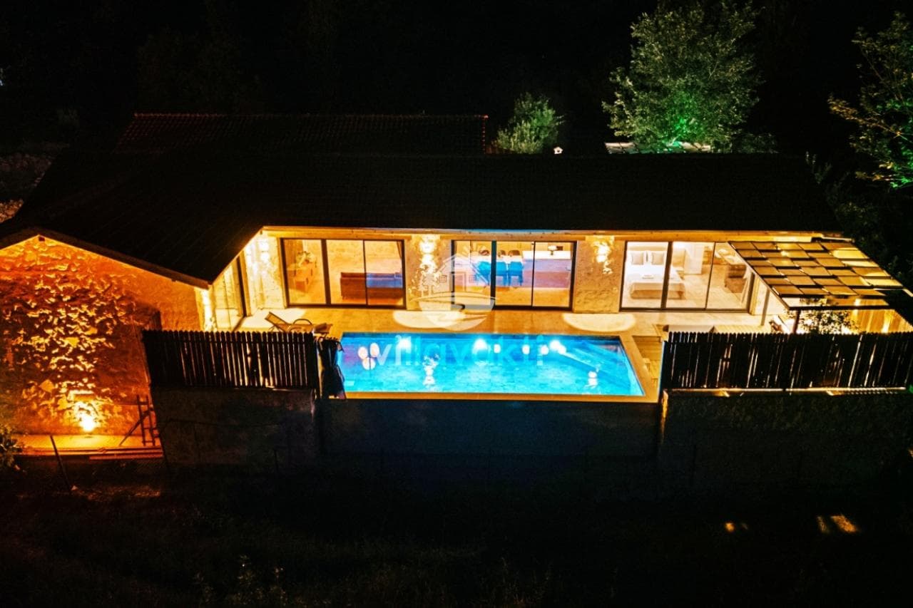 Villa Alaph'ın gece havuzlu ve aydınlatmalı dış cephesi.