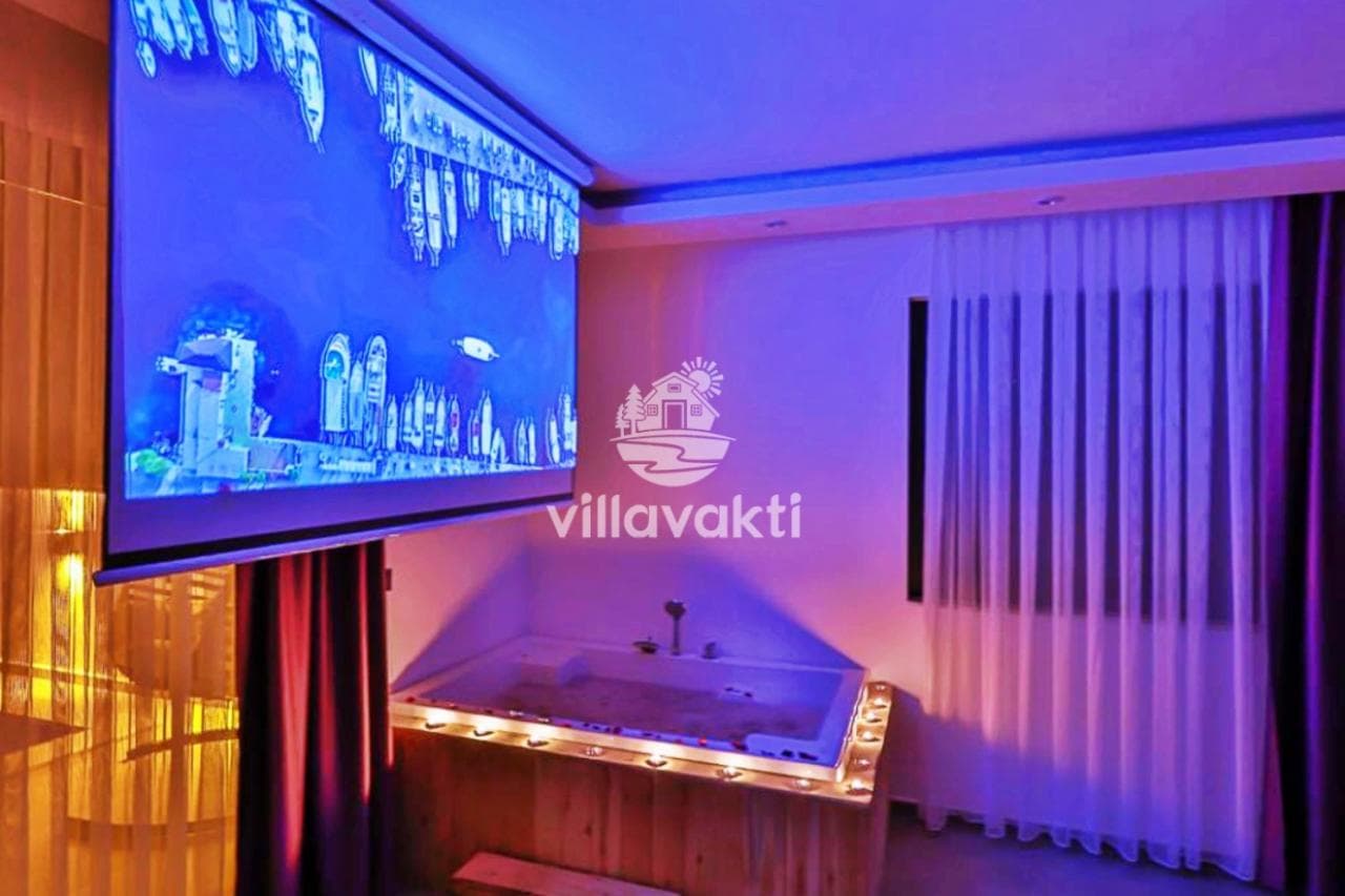Mor ışıklandırmalı yatak odasında jakuzi ve duvarda projeksiyon perdesi