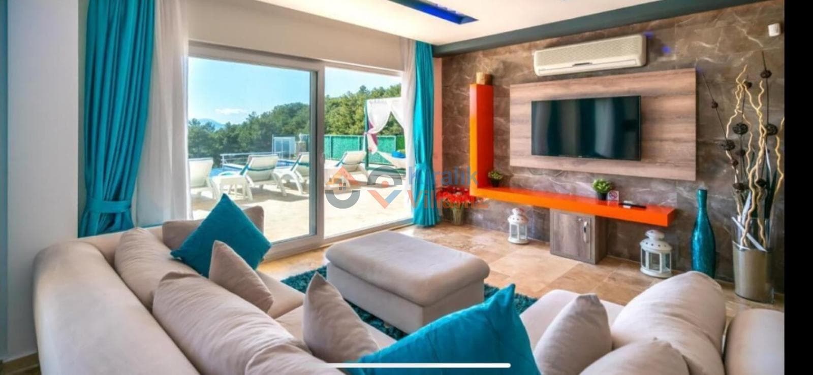 Turuncu raflı televizyon ünitesi ve bej koltuk takımı bulunan salondan havuz manzarası görünüyor.