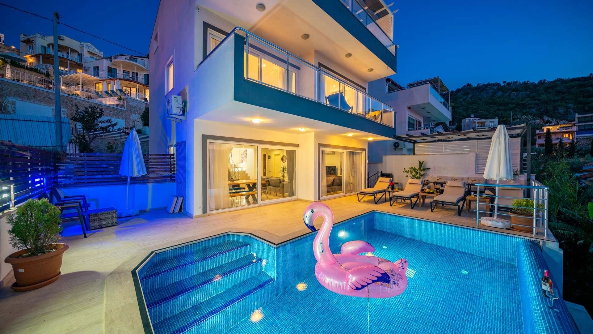 Gece aydınlatmalı, flamingo deniz yatağı bulunan özel havuzlu villa dış cephesi.