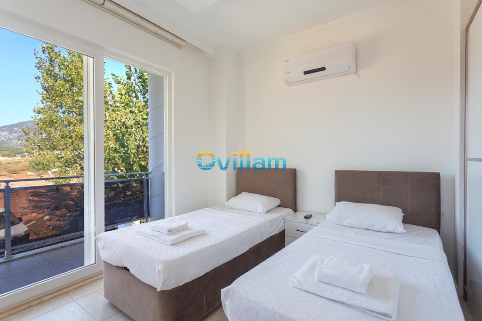 Balkon kapısı olan, iki tek kişilik yataklı aydınlık yatak odası.