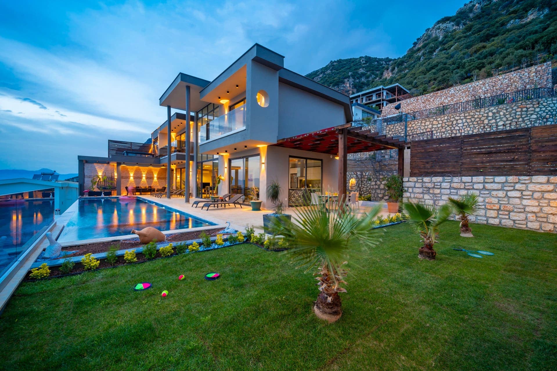 Akşam ışıklandırmalı havuzu ve modern cephesiyle villa dış görünümü.