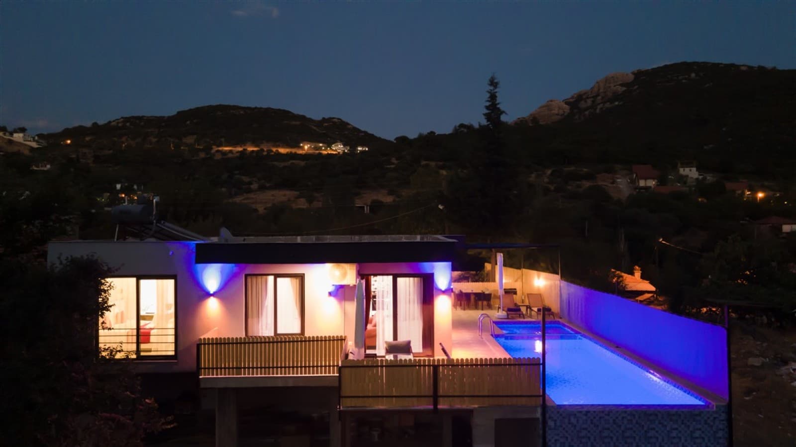 Aydınlatmalı havuzu ve balkonlu cephesiyle gece vakti villa dış görünümü.