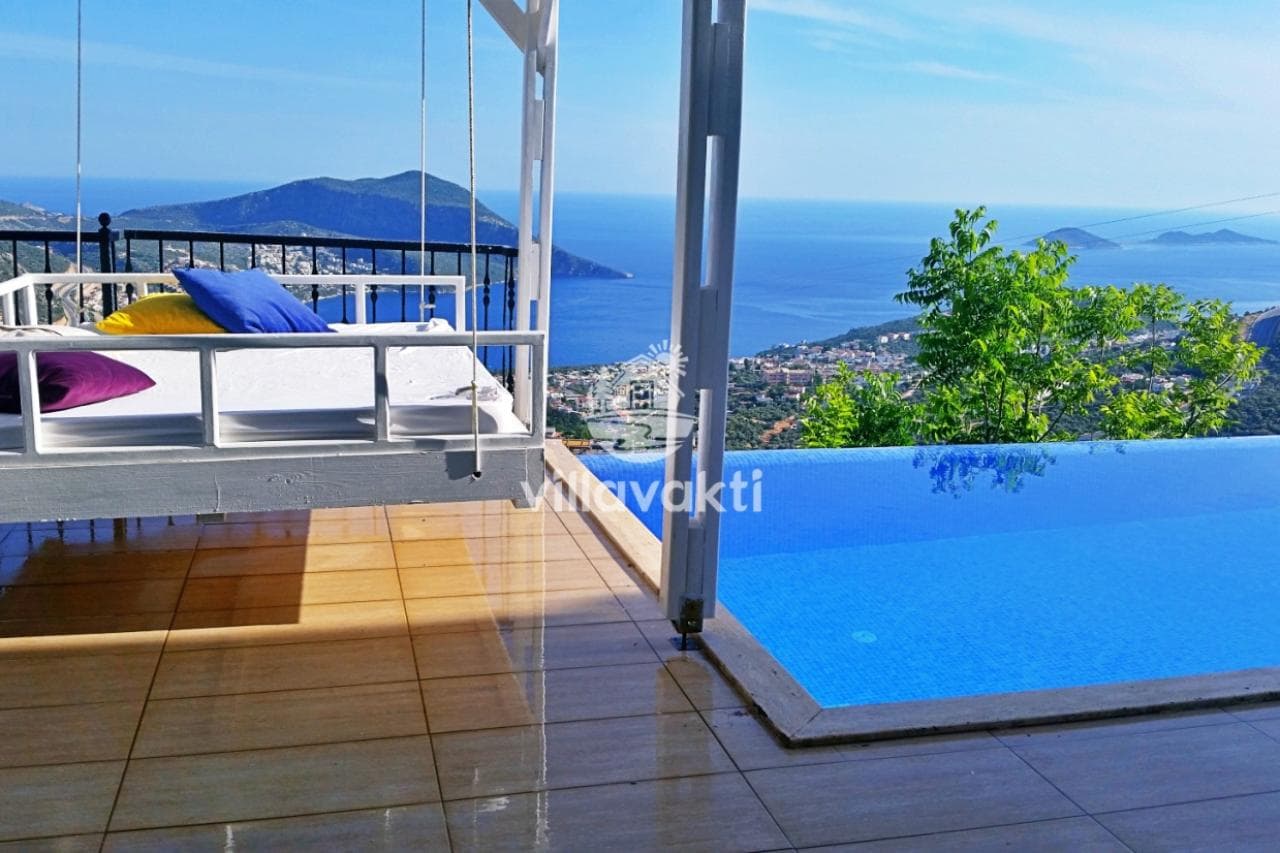 Havuz başında asılı beyaz salıncak yatak ve panoramik deniz manzarası bulunuyor.