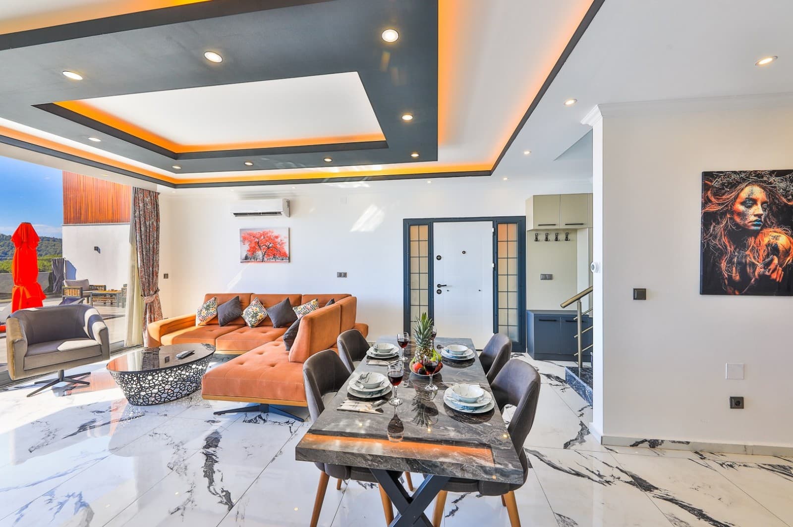 Turuncu koltuk takımı ve şık aydınlatmalı tavanıyla modern salon ve yemek alanı.