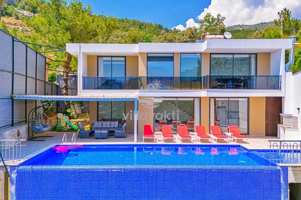 Önünde havuz bulunan, şezlonglu ve oturma gruplu iki katlı modern villa.
