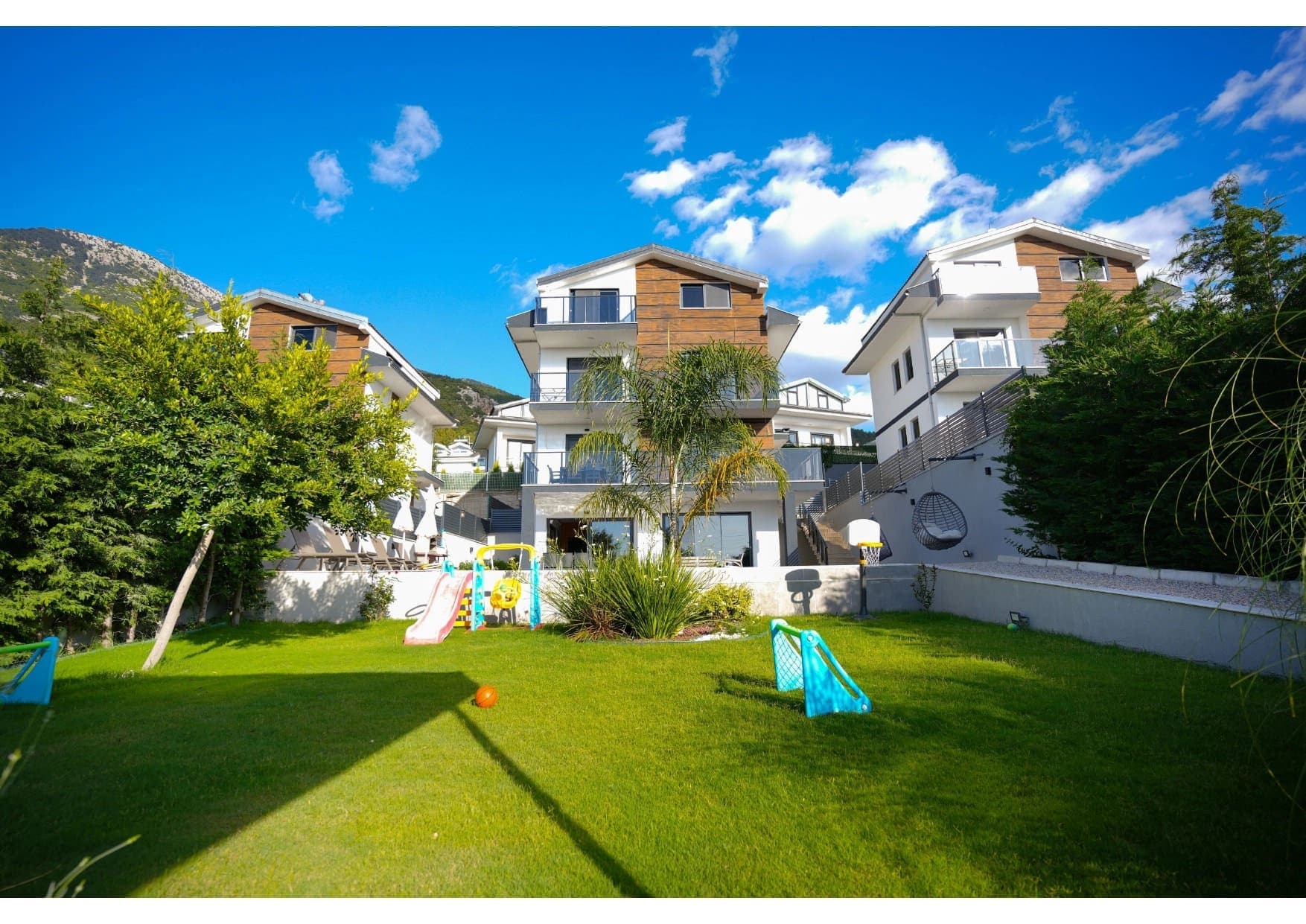 Bahçesinde çocuk oyun parkı ve havuz bulunan modern dış cepheli villa.