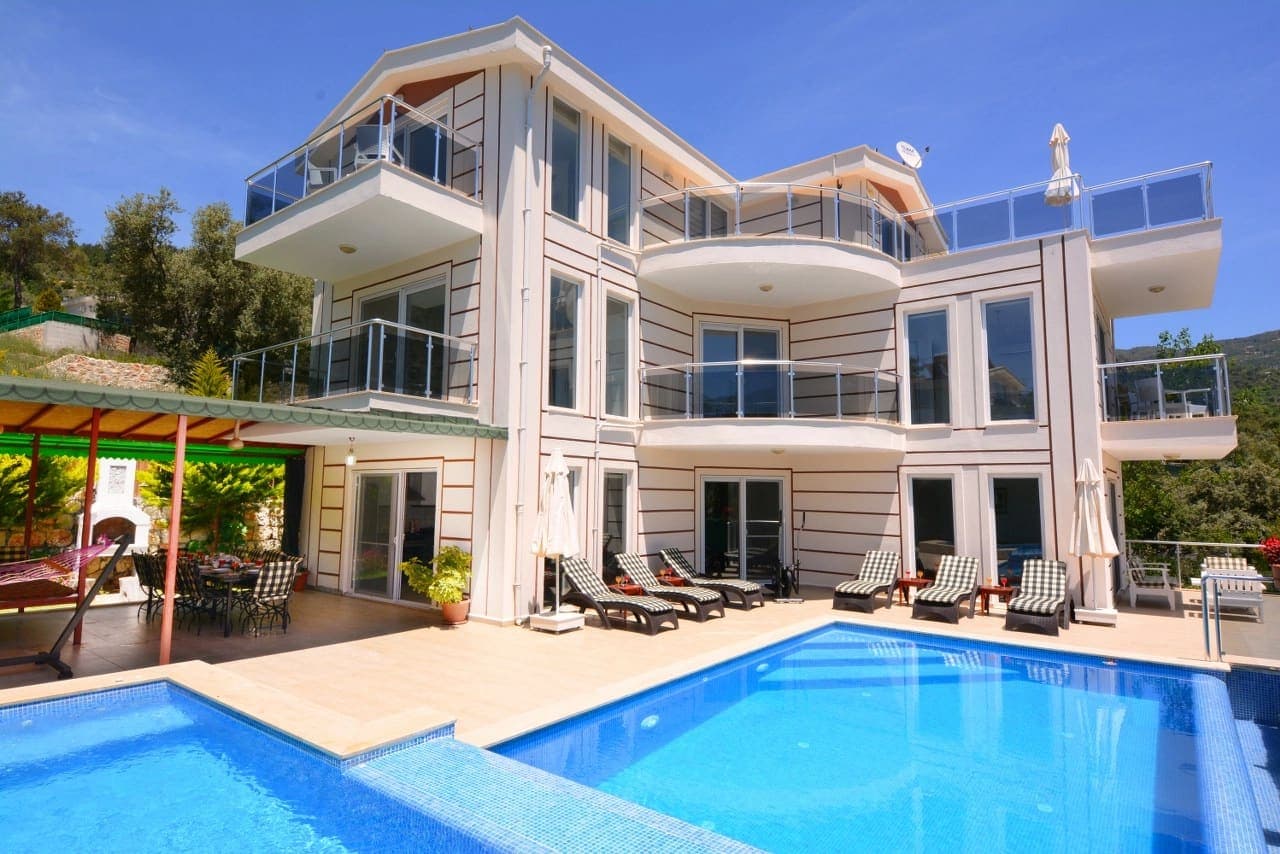 Üç katlı, balkonlu ve geniş pencereli modern villanın havuzlu dış cephesi.