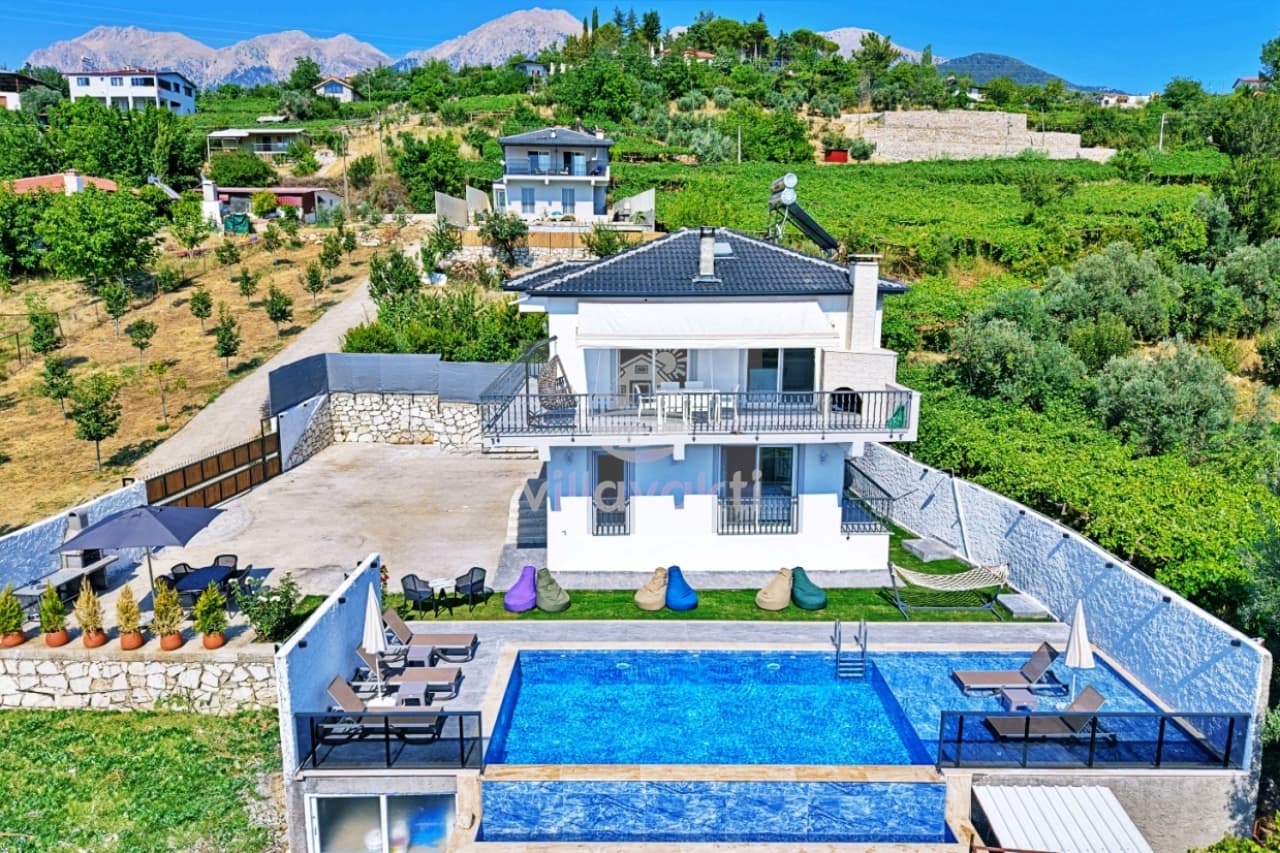 Dağ manzaralı, özel havuzlu ve geniş bahçeli beyaz dış cepheli villa.