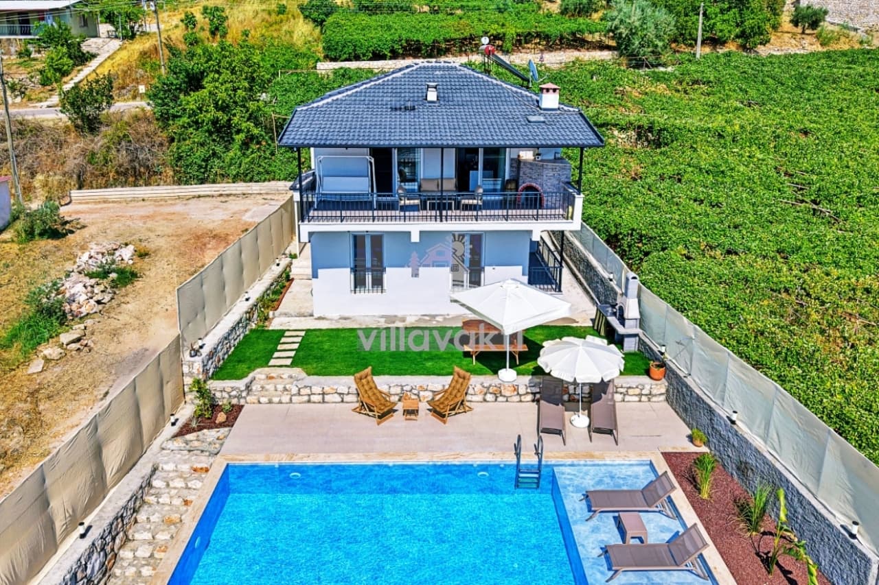 Bahçesinde havuz, şezlonglar ve çardak bulunan iki katlı müstakil villa.