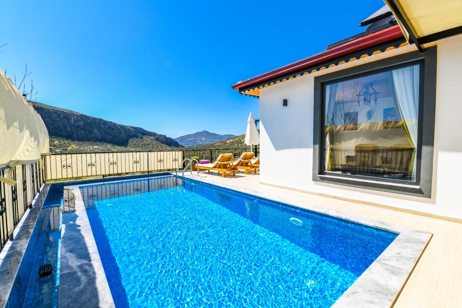 Dağ manzaralı havuz ve güneşlenme terası olan villa dış cephesi.