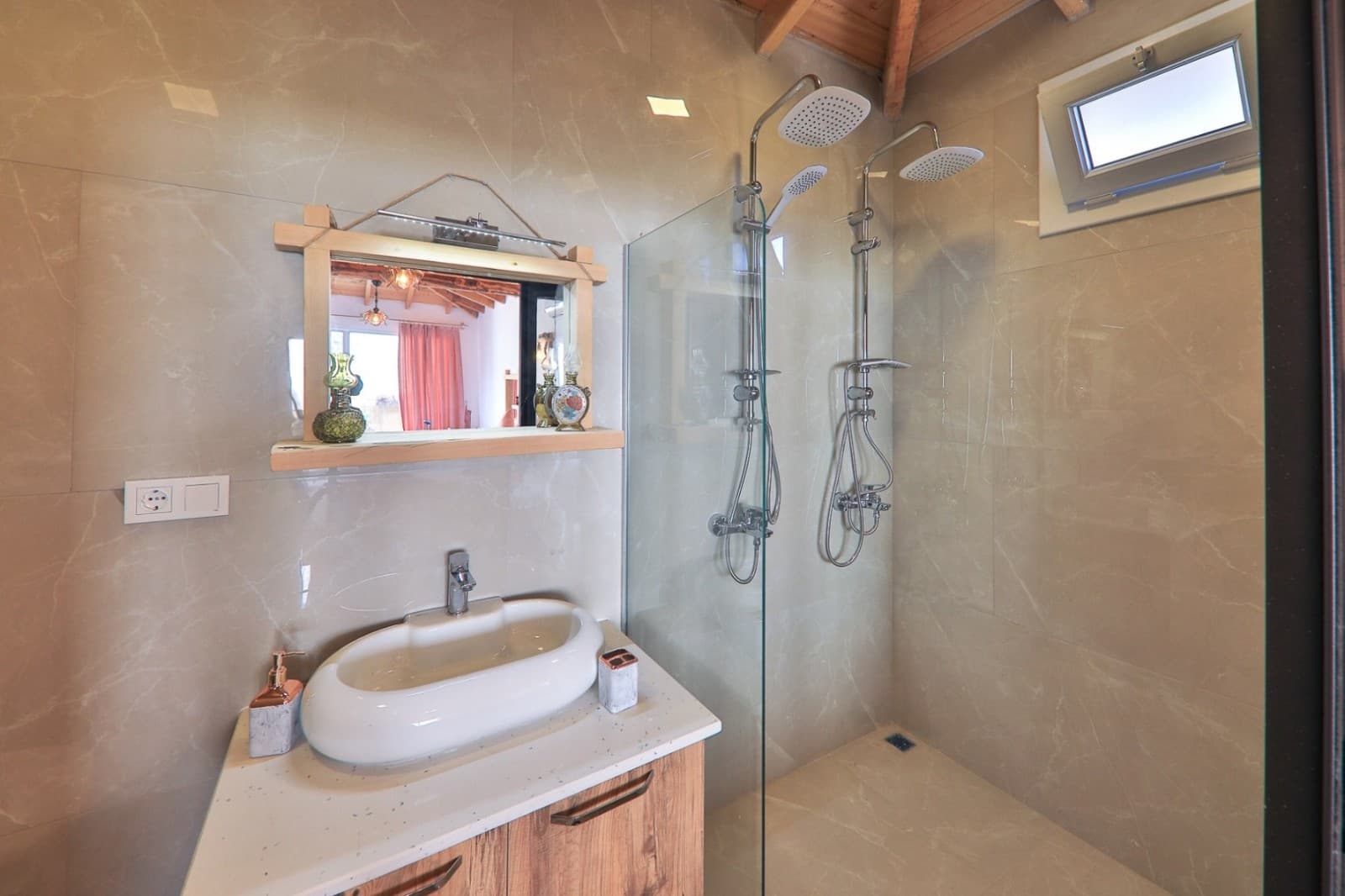 Bej tonlarında banyoda duş kabini ve ahşap çerçeveli lavabo.