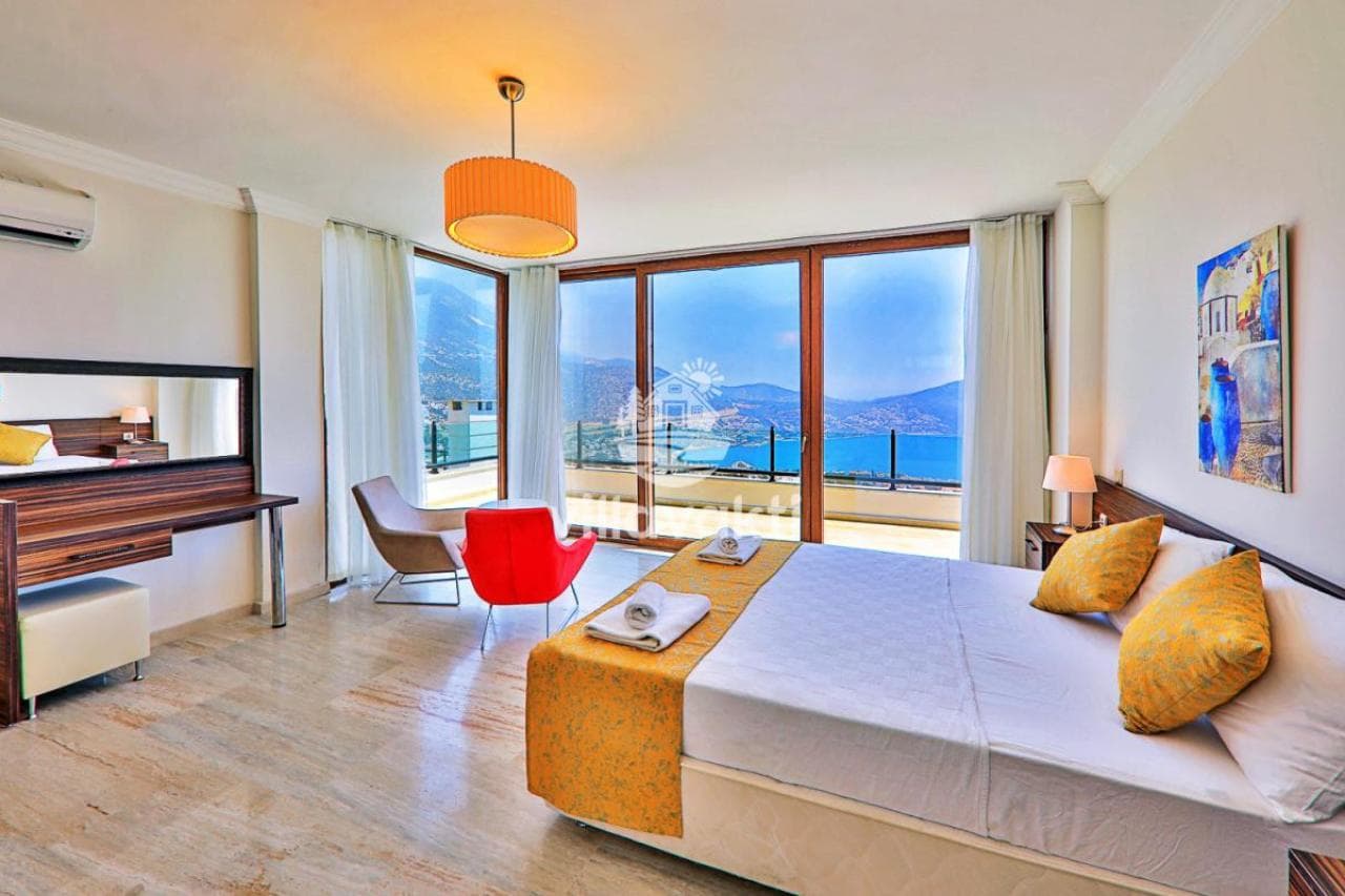 Deniz manzaralı, çift kişilik yataklı, kırmızı sandalyeli ve balkon çıkışlı aydınlık yatak odası.