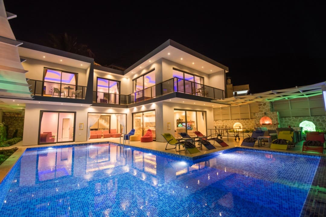 Gecenin karanlığında havuzlu ve ışıklandırılmış iki katlı lüks villa.
