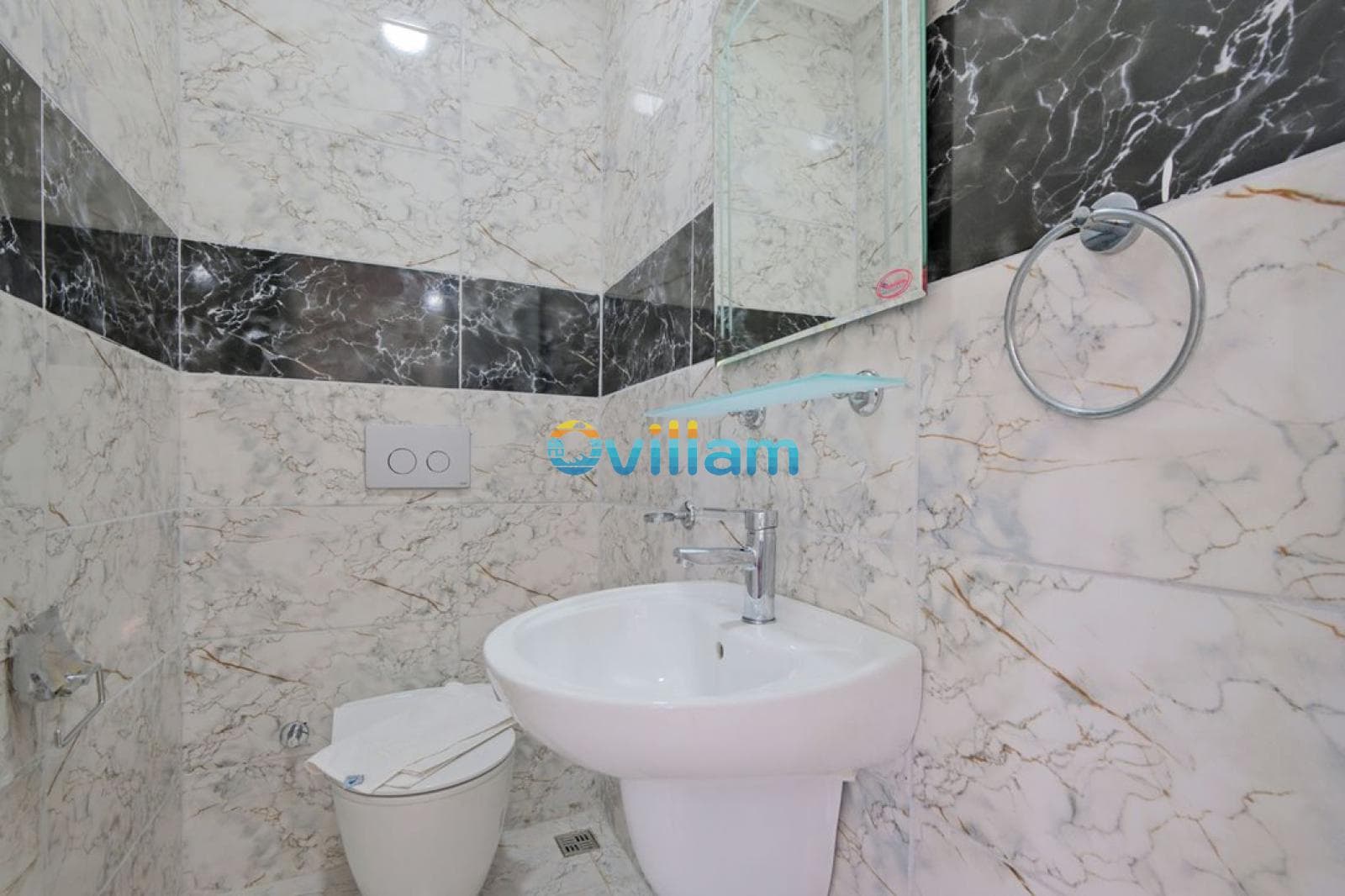 Mermer görünümlü duvar kaplamalı küçük banyo, beyaz lavabo ve klozet.