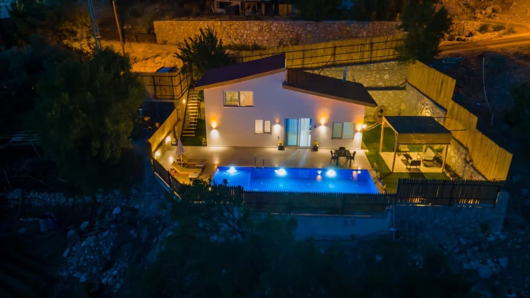 Gece aydınlatmalı havuzu, şezlongları ve çardaklı oturma alanı bulunan bahçeli müstakil villa.