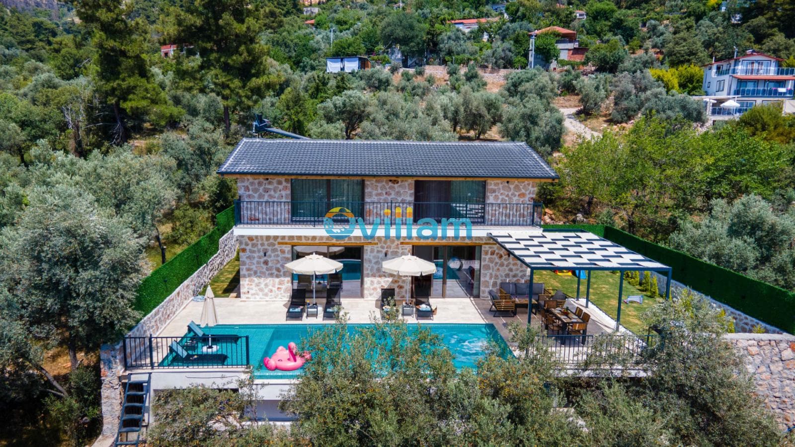 Zeytin ağaçları arasında taş mimarili villa, özel havuz ve güneşlenme terasının kuş bakışı görünümü.