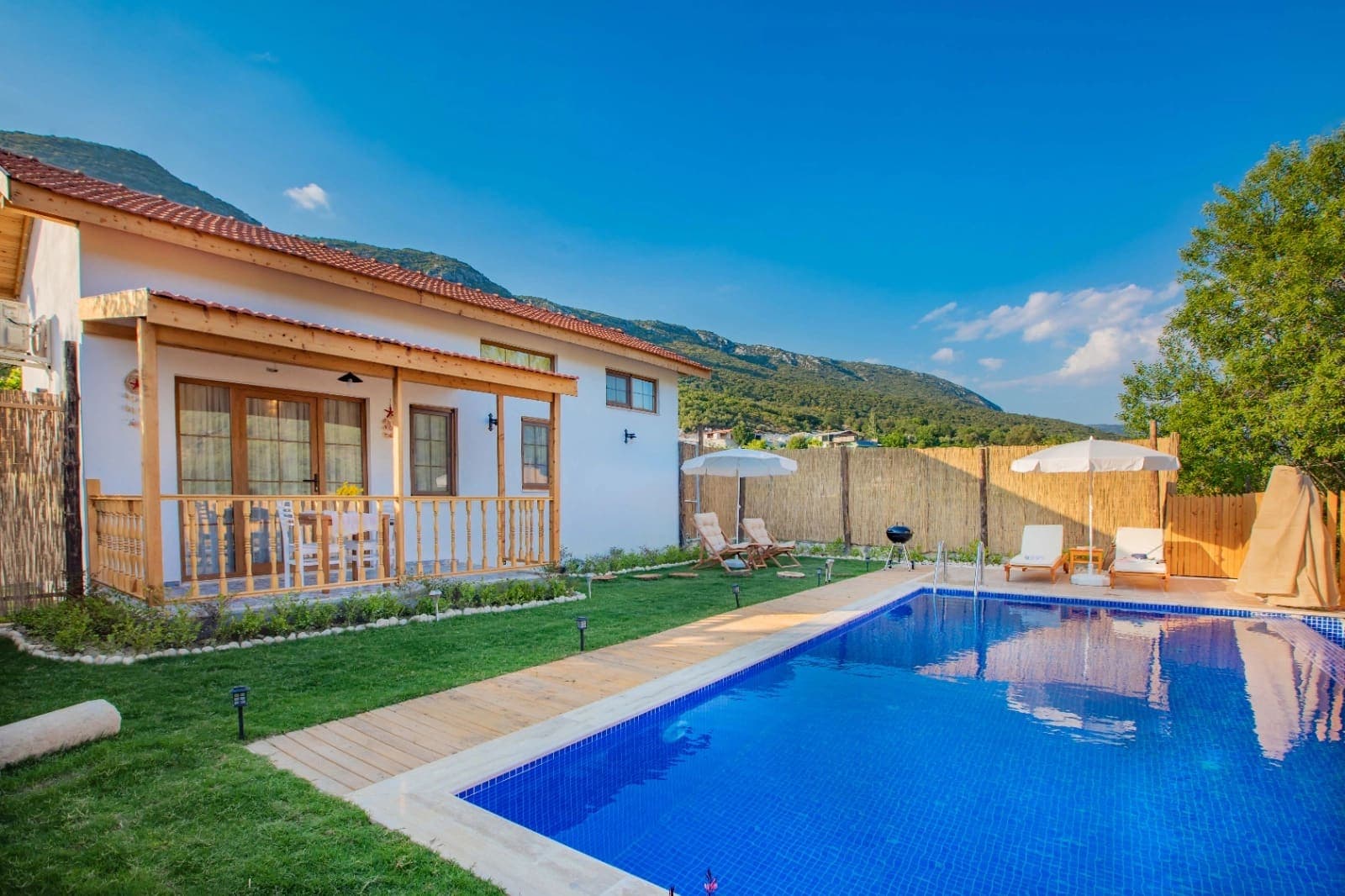 Ahşap verandası ve havuzu olan dağ manzaralı tek katlı villa