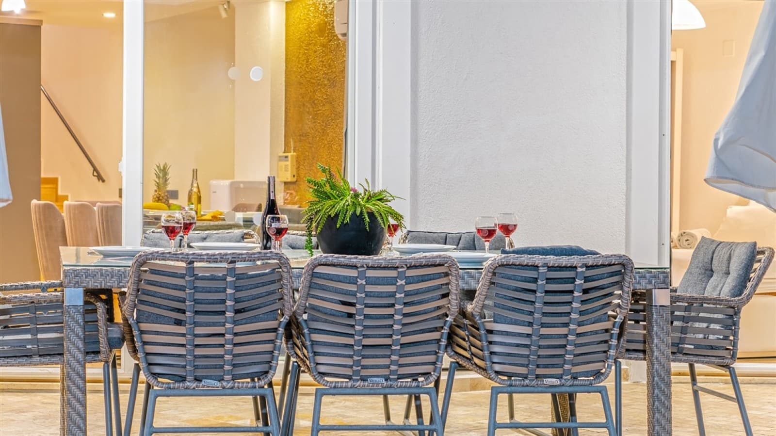 Verandada gri minderli sandalyeler ve üzerinde kadehler bulunan masa.