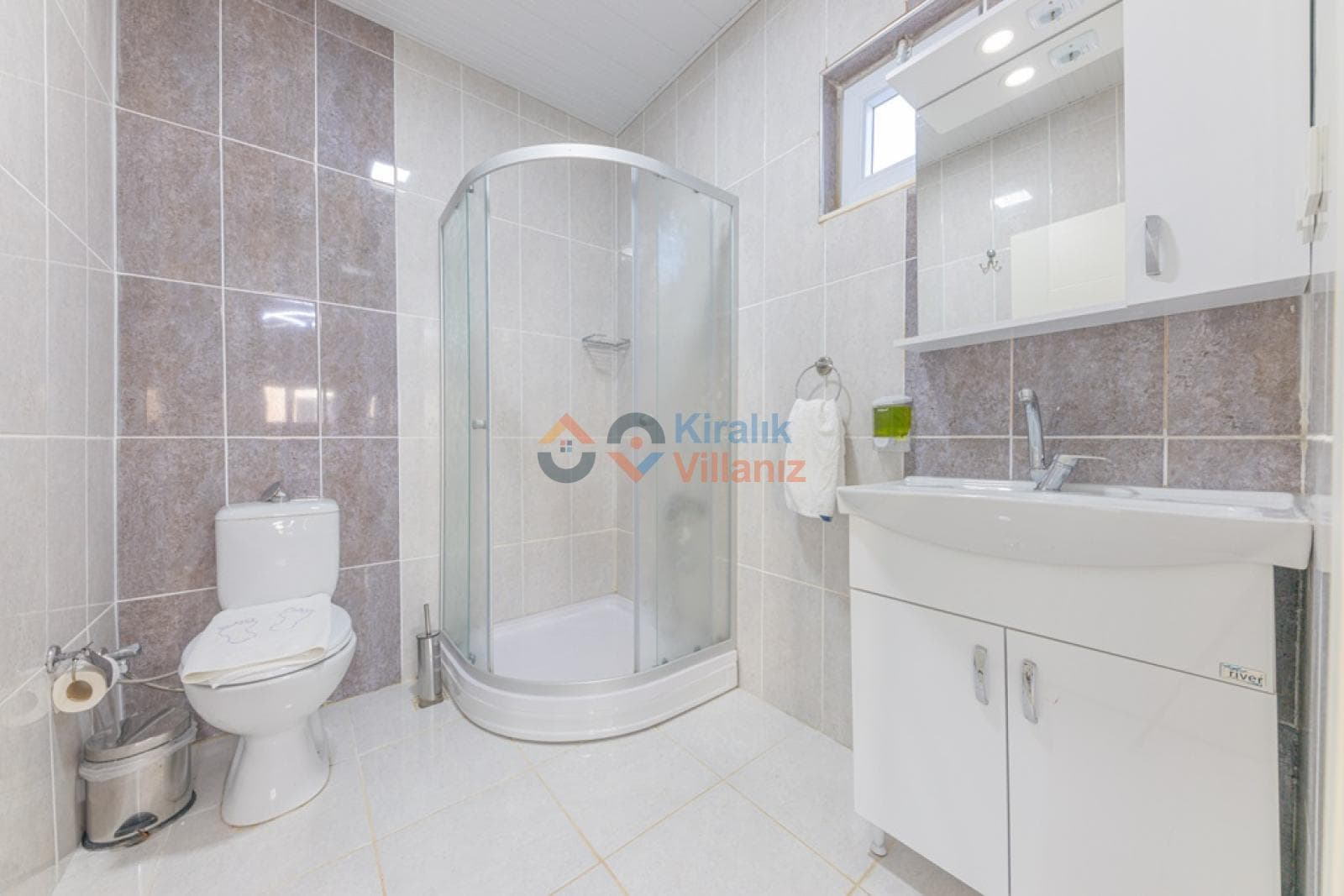 Beyaz banyo dolabı, klozet ve oval cam duşakabin.
