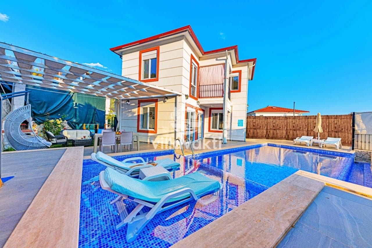 Villa önünde mavi şezlongların bulunduğu açık yüzme havuzu.