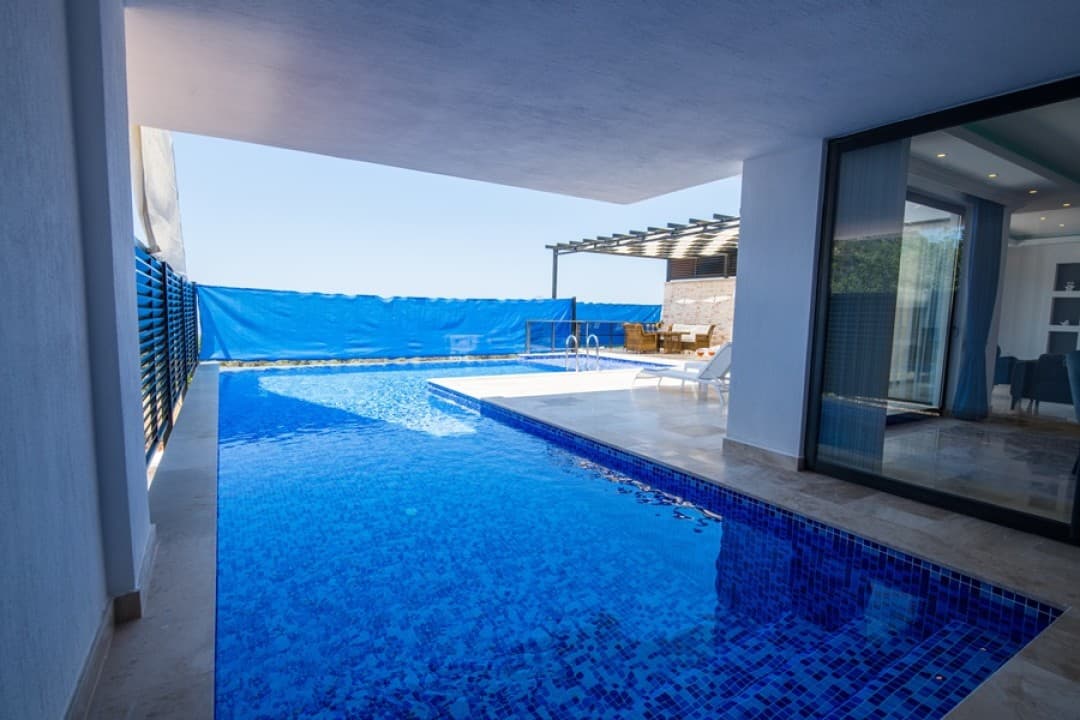 Villa Blue Sirena'nın gölgelikli açık havuzu ve havuz başı şezlongları.