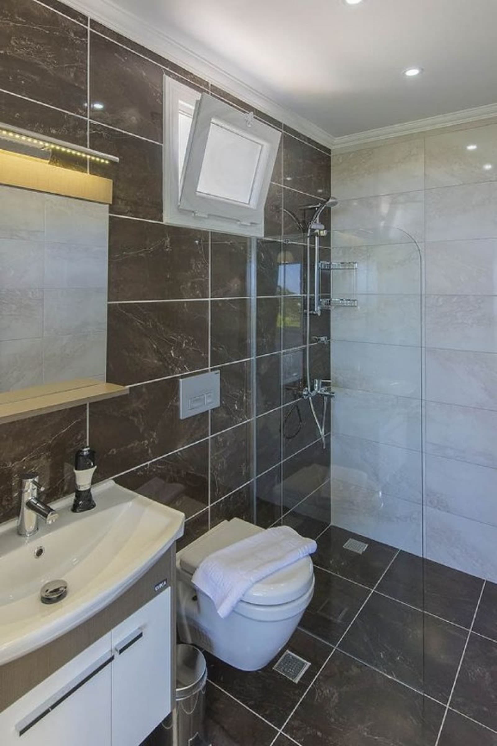 Kahverengi ve beyaz seramik kaplı duşakabinli banyo.