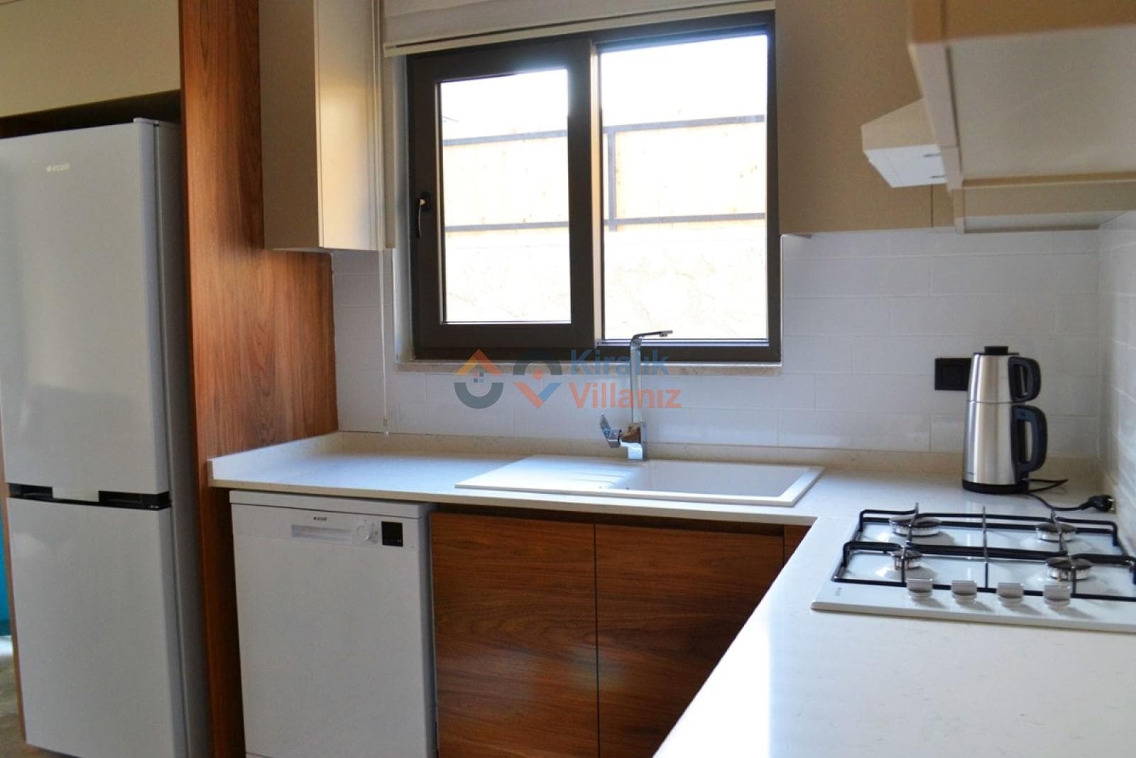 Beyaz tezgahlı, ahşap dolaplı ve ankastre ocaklı modern mutfak.