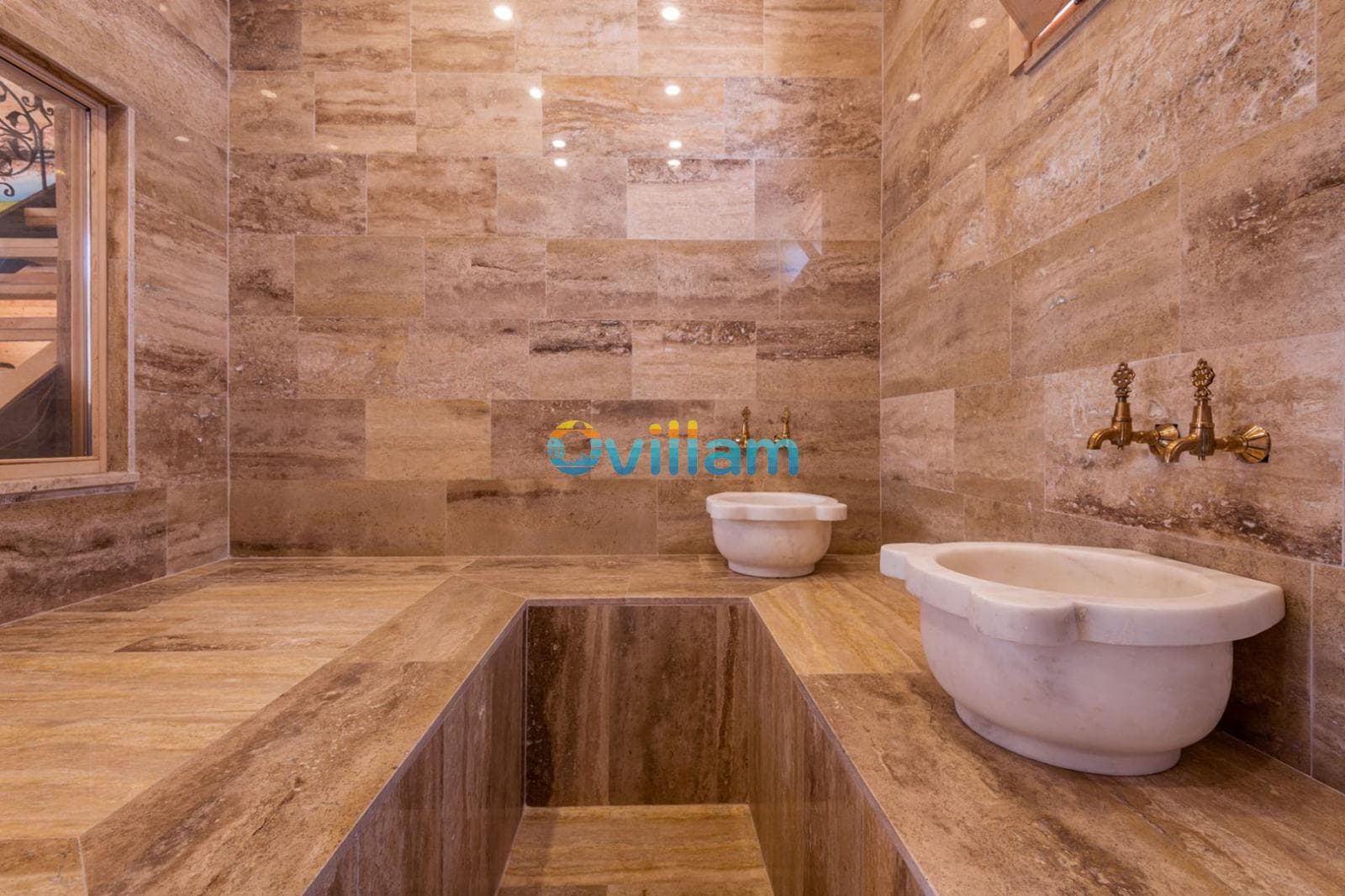 Traverten kaplı geleneksel hamam alanında kurnalar ve gömme yıkanma havuzu.