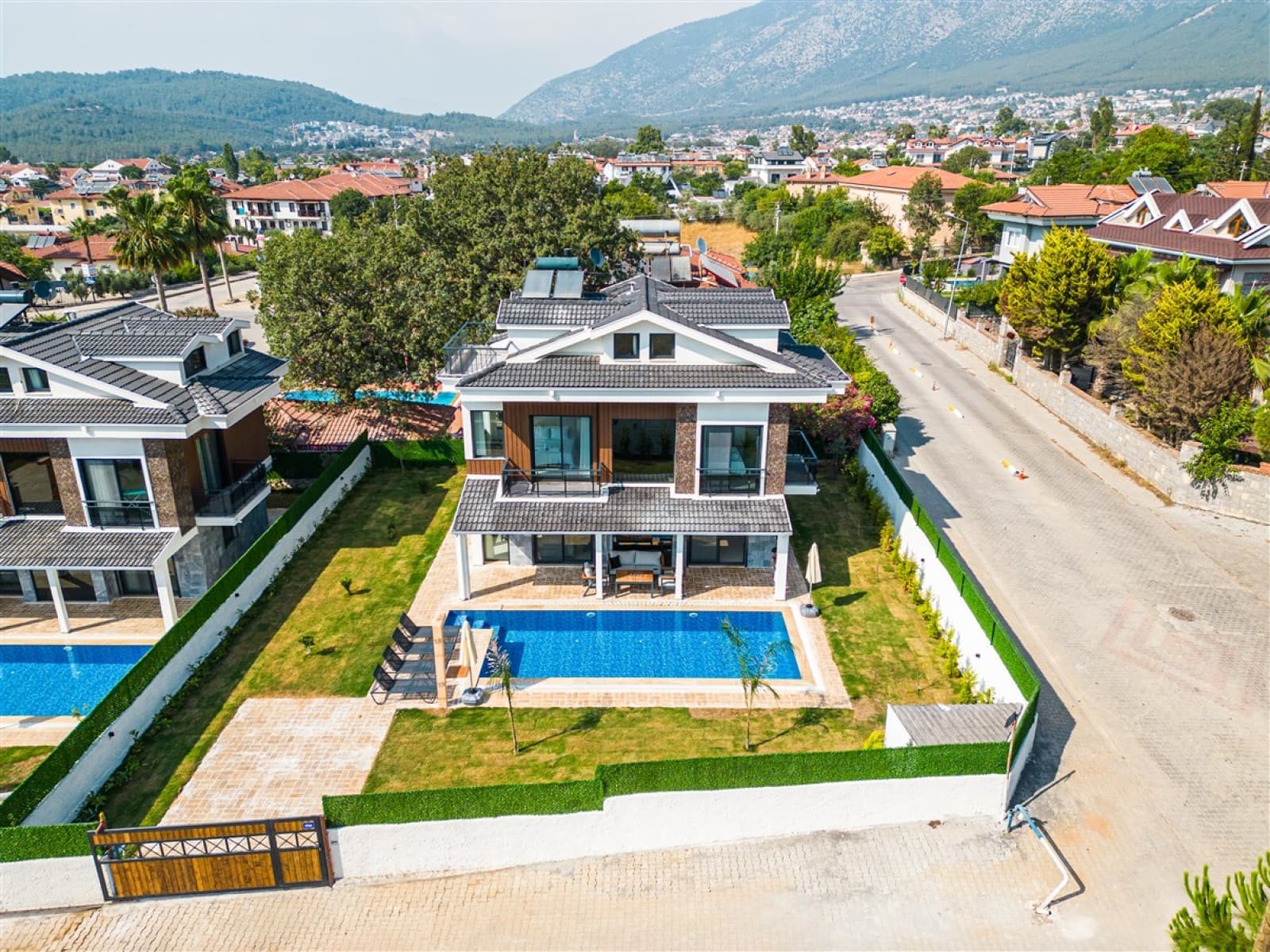 Yüzme havuzlu müstakil villanın ve sokağın kuş bakışı görünümü.