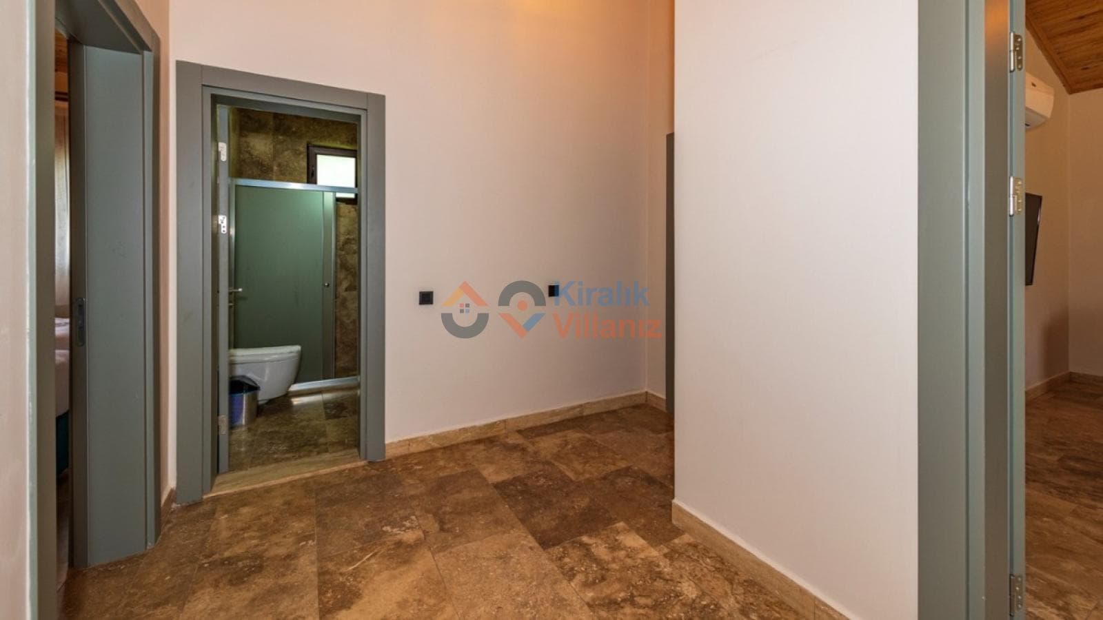 Seramik zeminli koridor ve açık kapıdan görünen banyo.