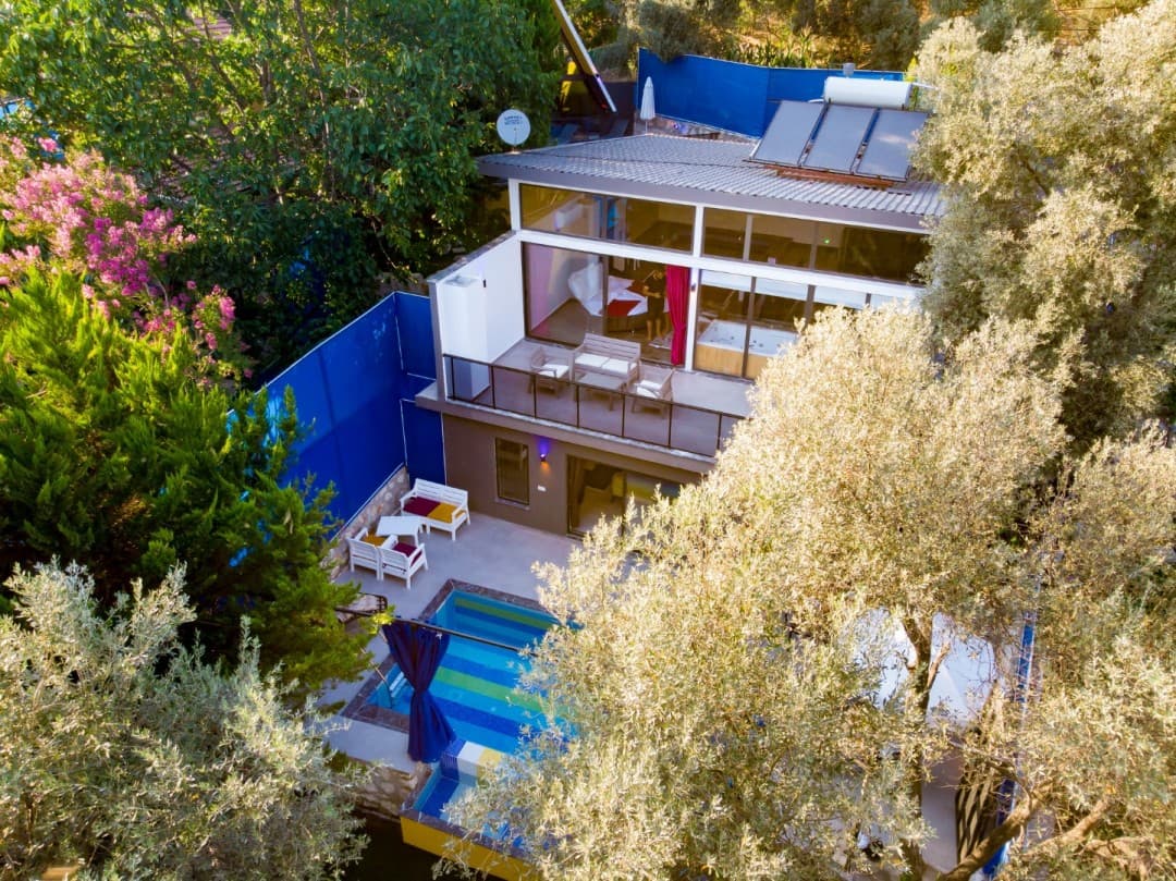 Ağaçlar arasında havuzlu ve balkonlu iki katlı müstakil villa.