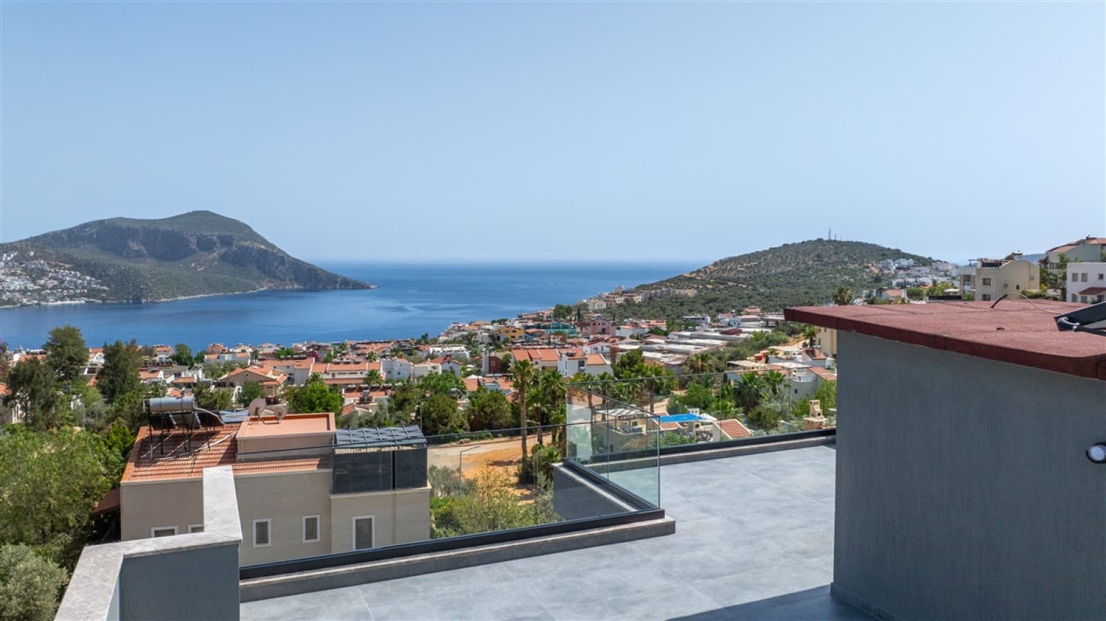 Balkondan deniz, dağlar ve yerleşim yeri manzarası.