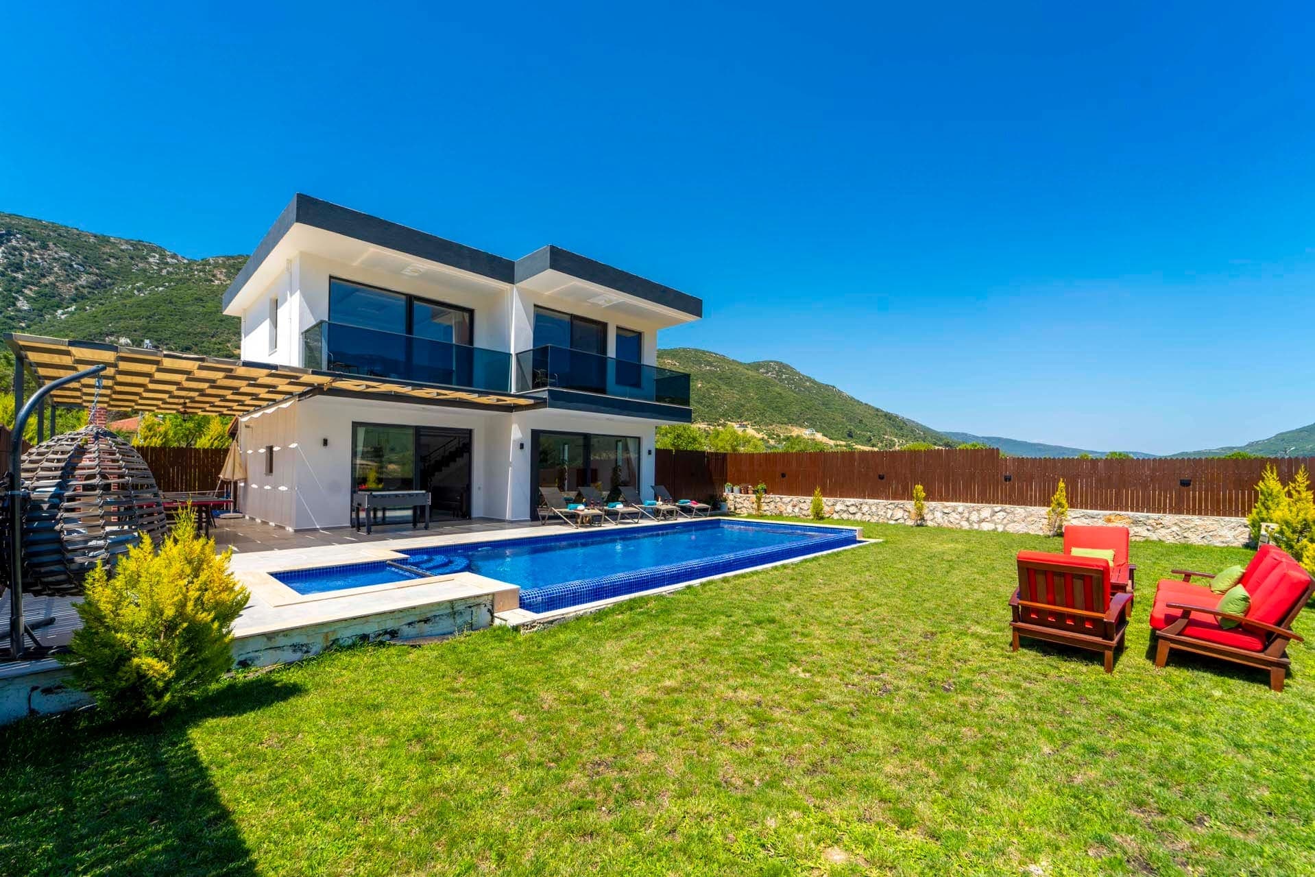 Dağ manzaralı geniş bahçesi ve havuzu olan iki katlı beyaz villa.