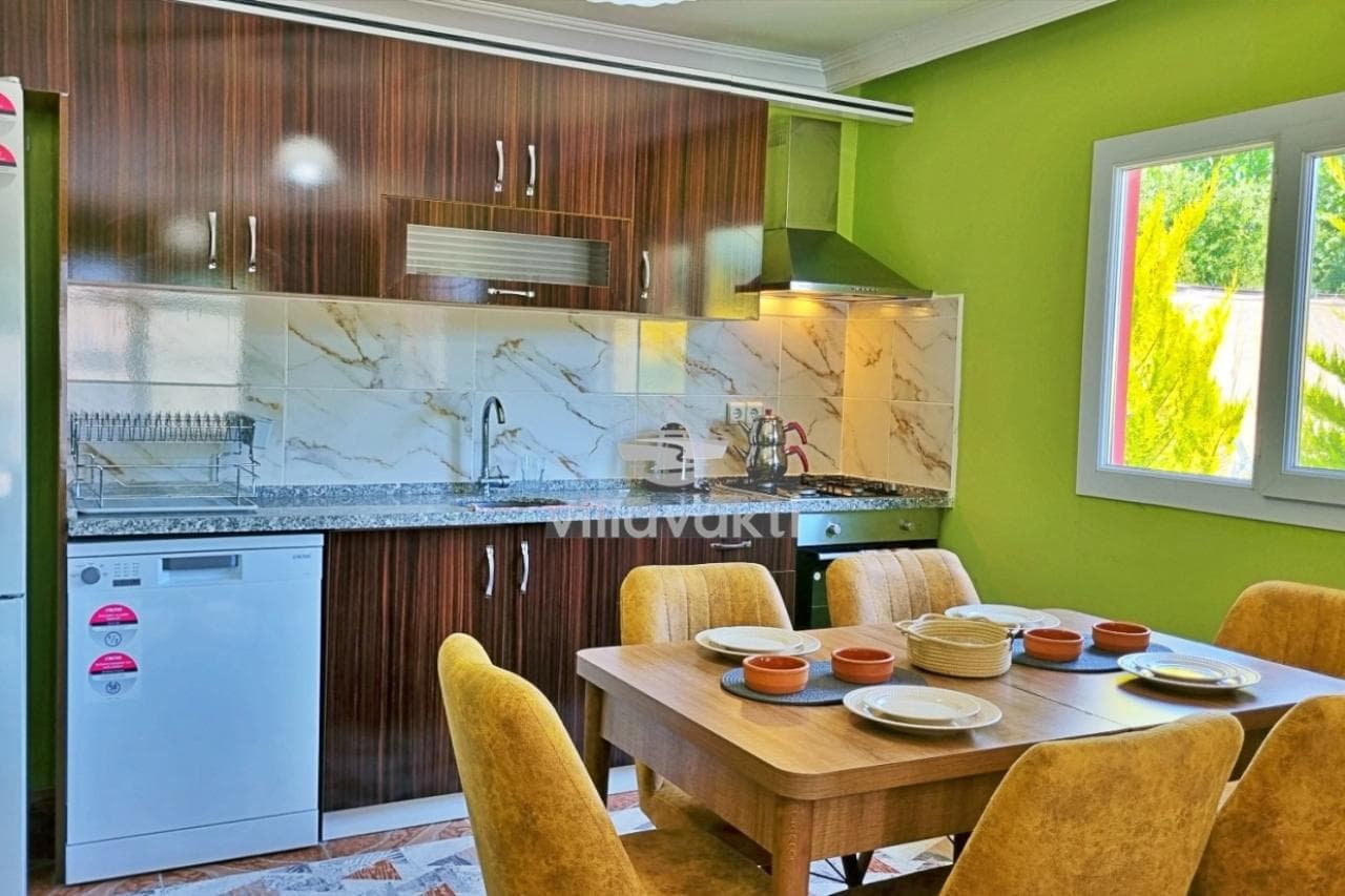 Ahşap dolaplı mutfak ve sarı sandalyeli yemek masası.