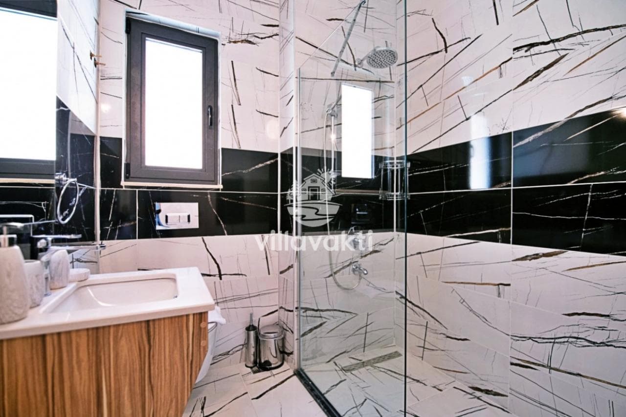Siyah beyaz mermer desenli duvar karolarına sahip banyo ve duşakabin.
