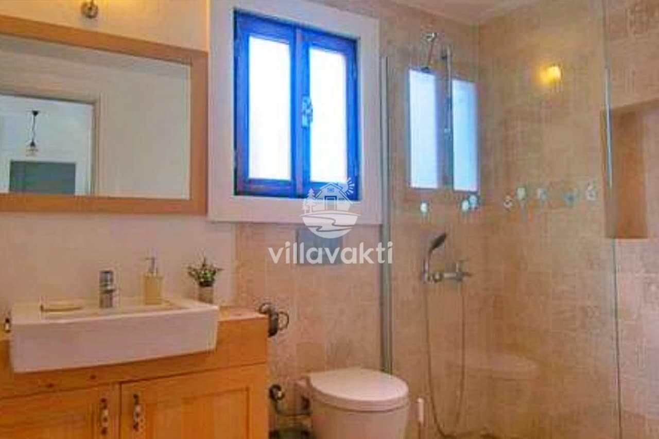 Ahşap dolaplı lavabo ve cam duş kabini bulunan banyo.
