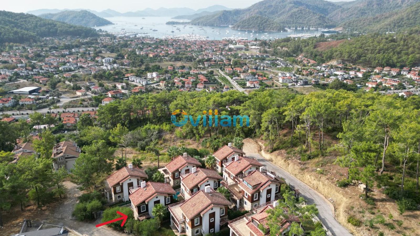 Orman içinde konumlanan villaların uzaktan deniz manzaralı genel görünümü.