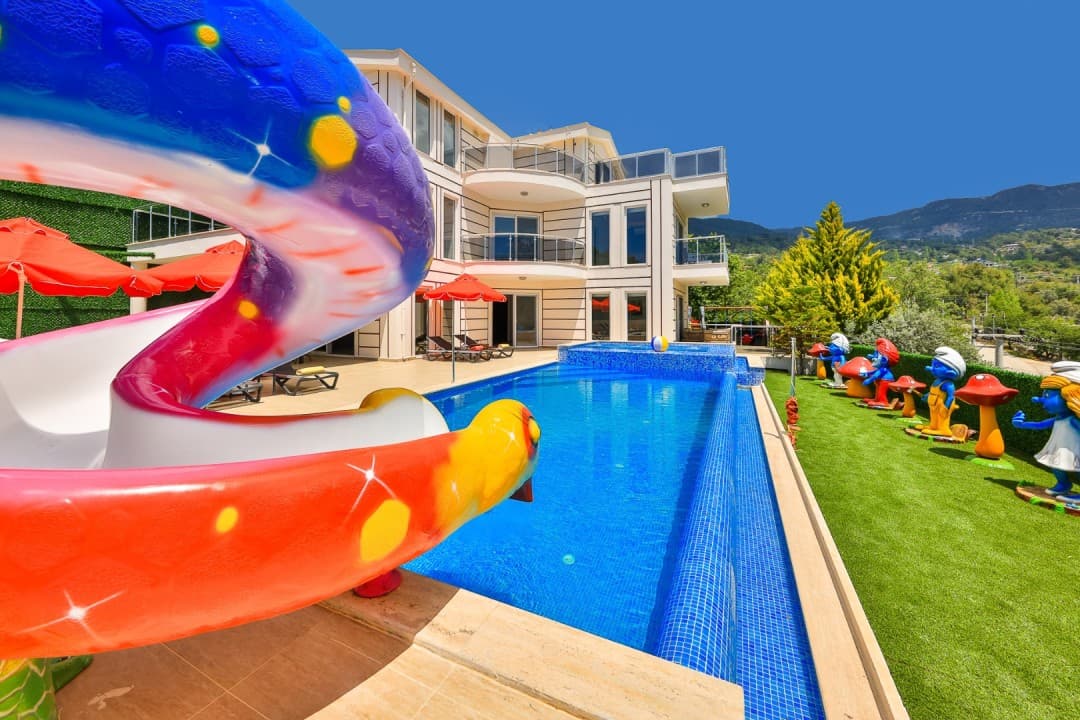 Renkli su kaydırağı, yüzme havuzu ve bahçesinde şirinler figürleri bulunan üç katlı villa.