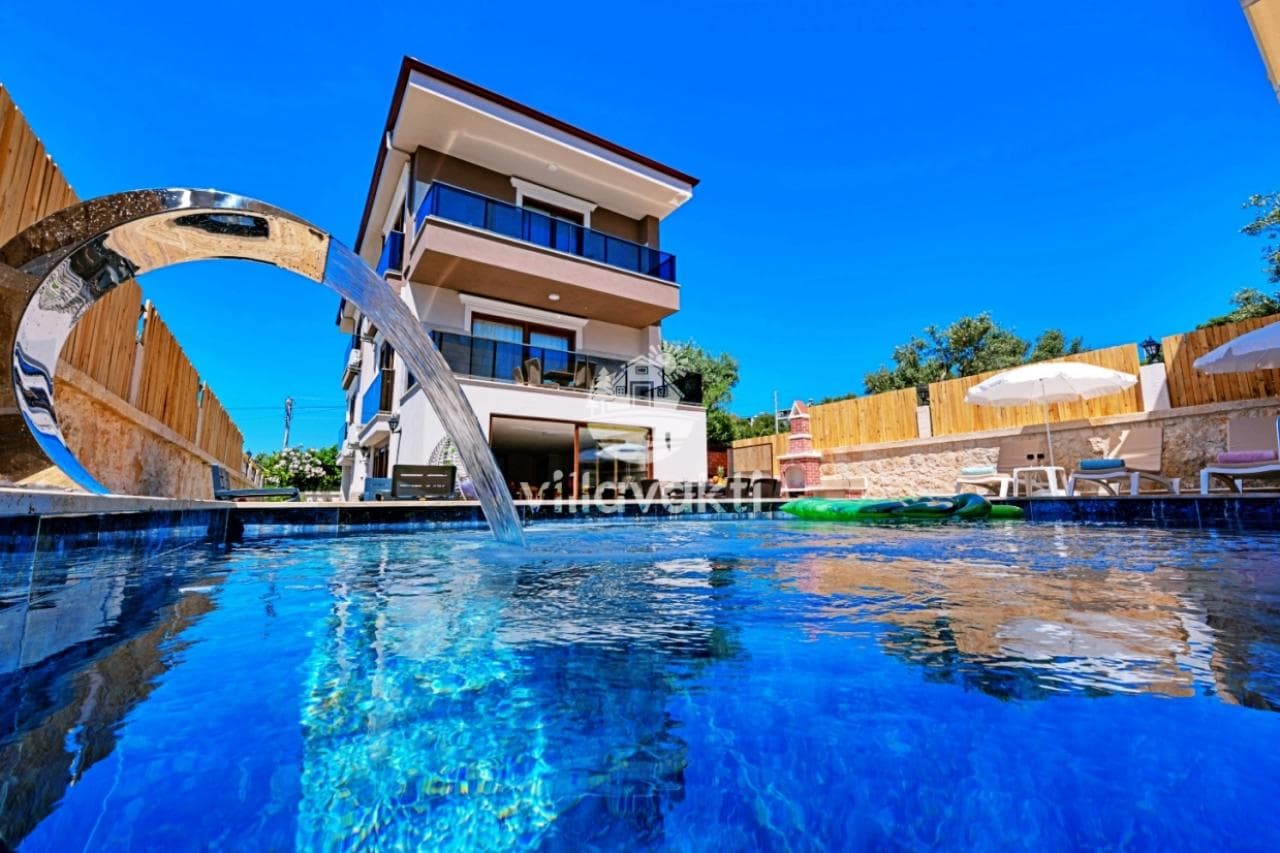 Ön planında havuz ve su fıskiyesi olan çok katlı modern villa.
