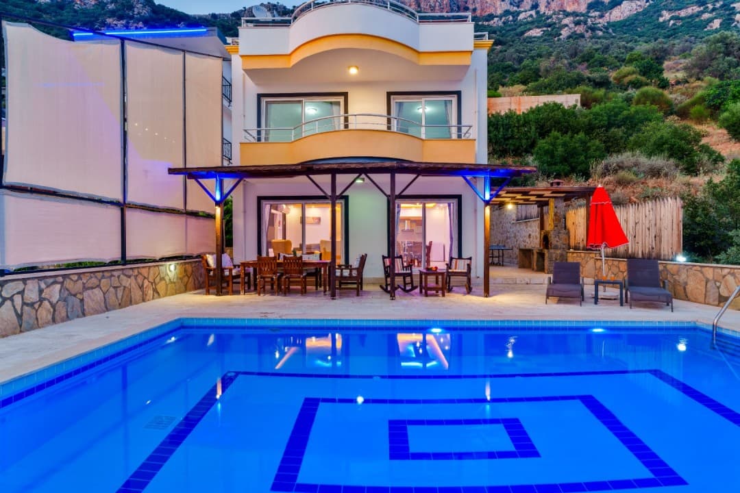 Önünde havuz bulunan, ahşap çardaklı, balkonlu ve akşam ışıklandırmalı iki katlı müstakil villa.