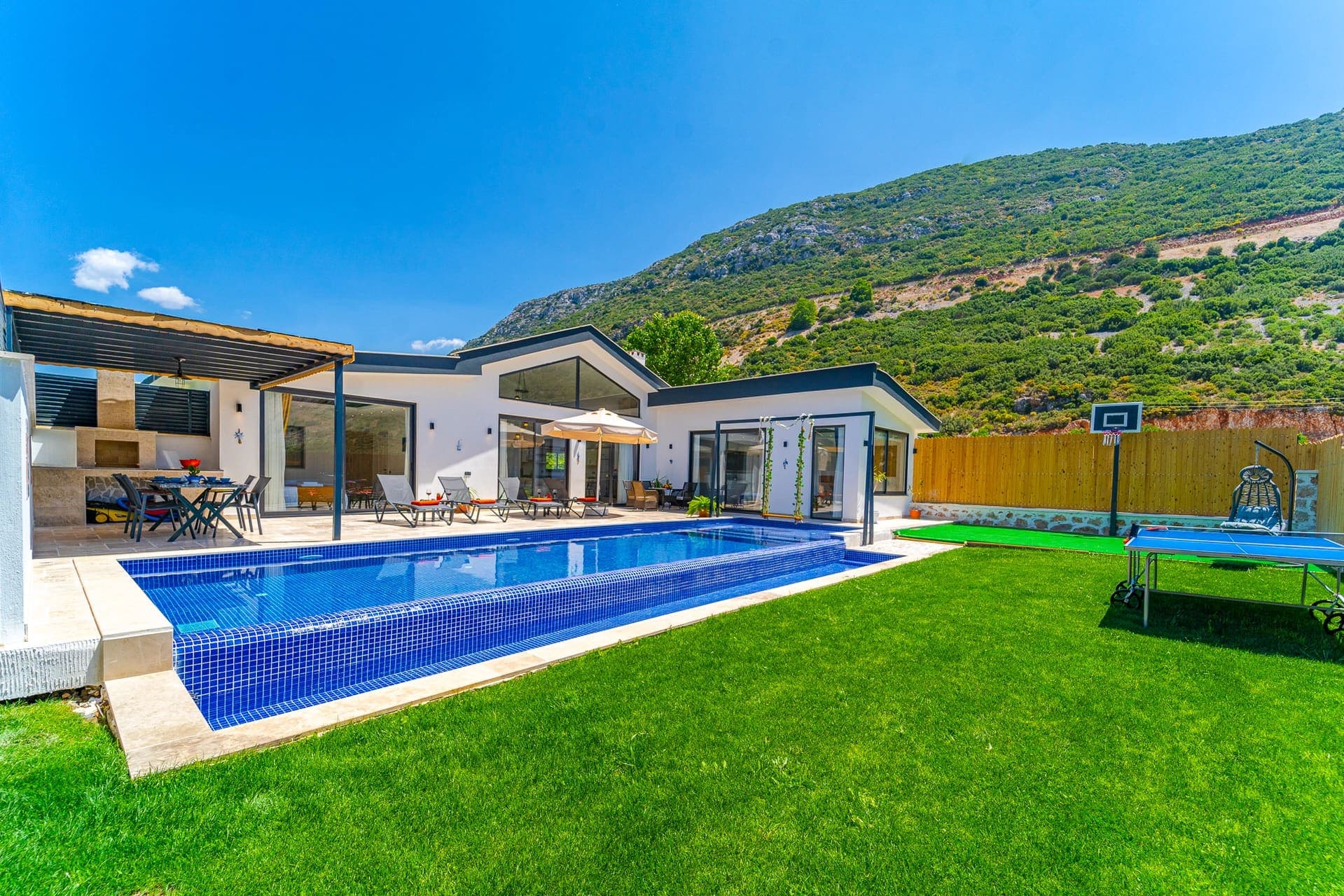 Çim bahçeli, açık havuzlu ve dağ manzaralı tek katlı villa.