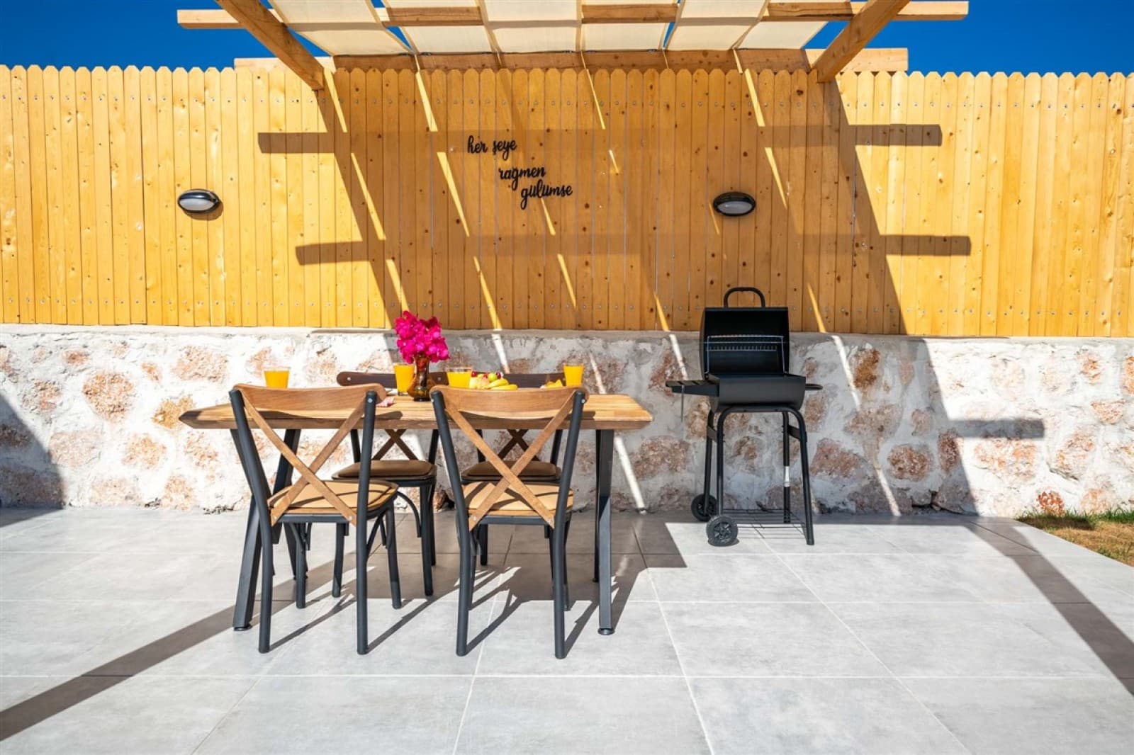 Ahşap çit önünde yemek masası ve barbekü mangal
