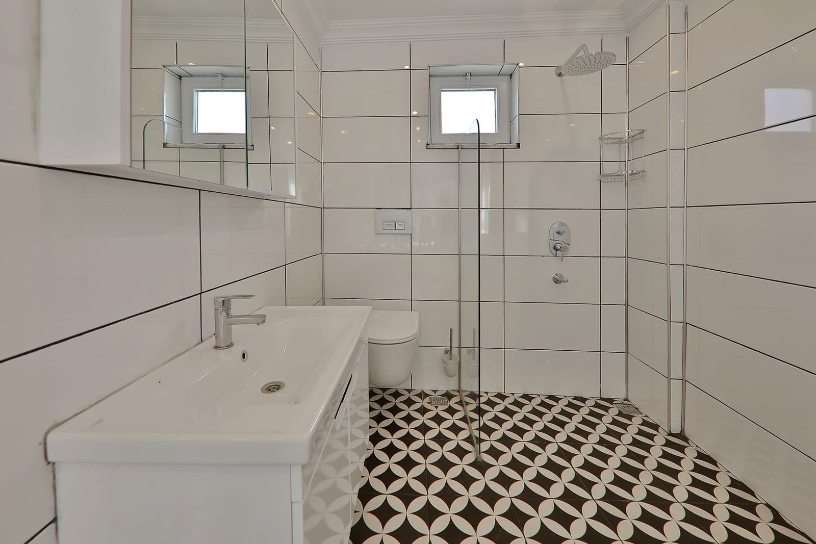 Beyaz fayanslı duş alanı, lavabo ve desenli zemin