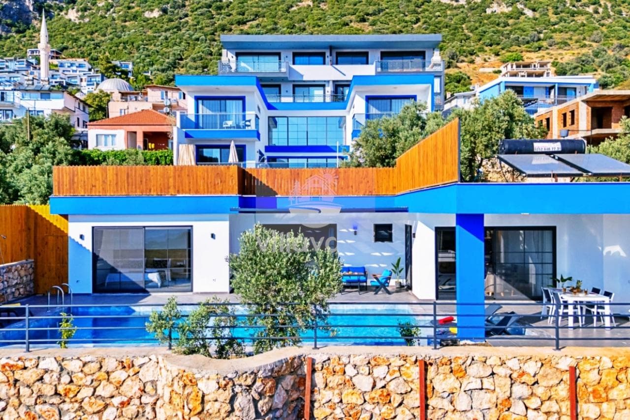 Dağ yamacında yer alan mavi detaylı modern villanın dış cephesi ve havuzu.